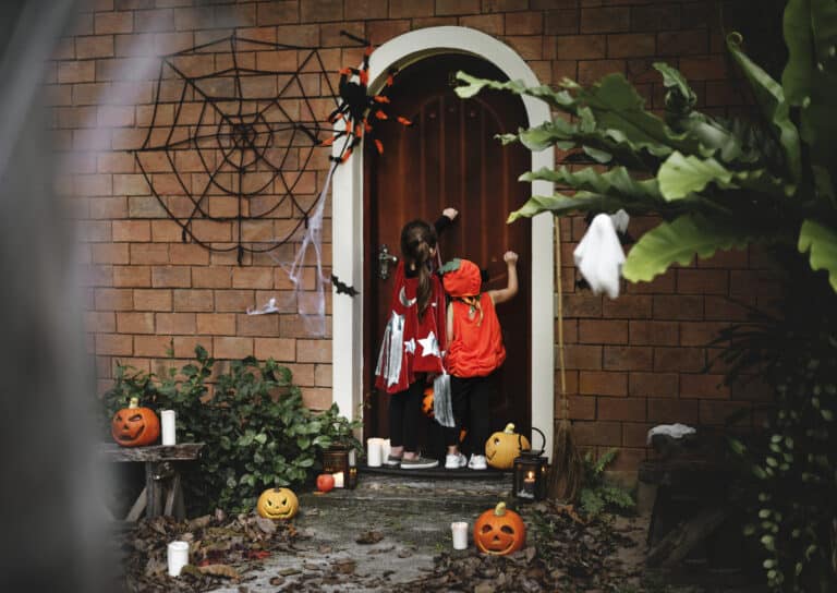 Children in costumes trick-or-treating at a decorated house, promoting safety tips to prevent a Halloween accident Houston from Attorney Don McClure, Personal Injury Attorney in Houston.