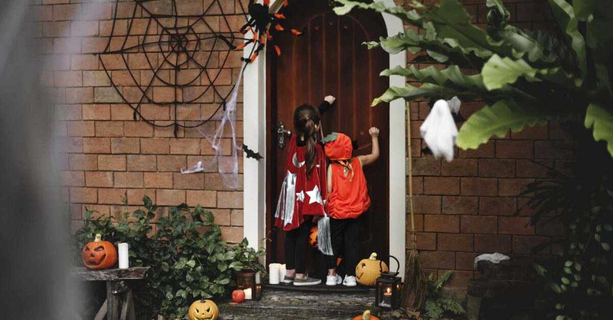 Children in costumes trick-or-treating at a decorated house, promoting safety tips to prevent a Halloween accident Houston from Attorney Don McClure, Personal Injury Attorney in Houston.