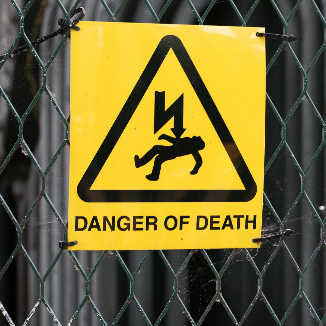 Warning sign on a fence showing a risk of electrocution at a worksite.