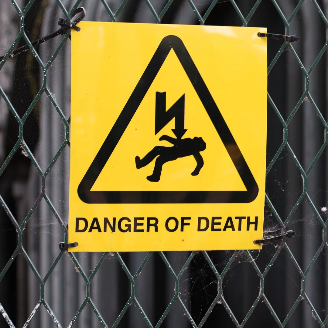 Warning sign on a fence showing a risk of electrocution at a worksite.